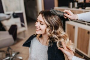 Person gently defining wet curls with conditioner in a bright bathroom.