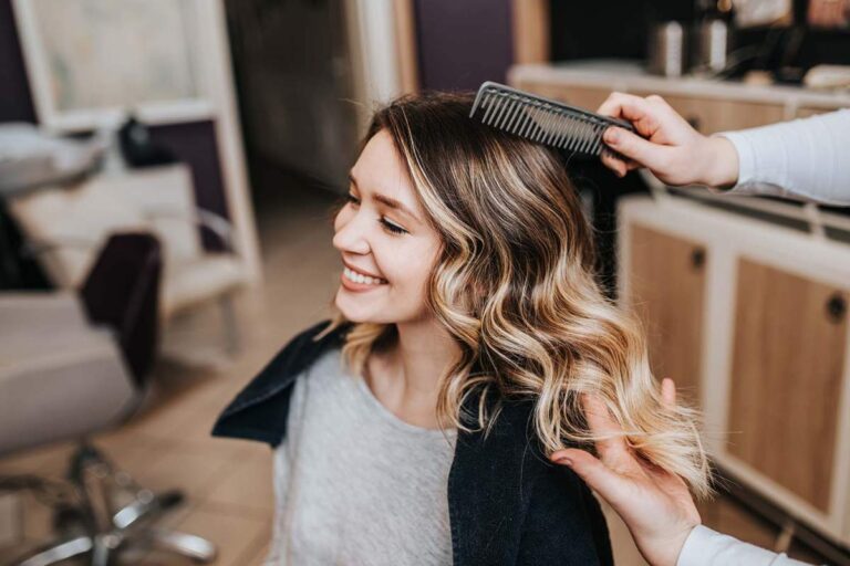 Person gently defining wet curls with conditioner in a bright bathroom.